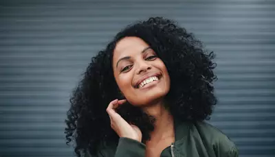 Mulher sorrindo com cabelo cacheado preto
