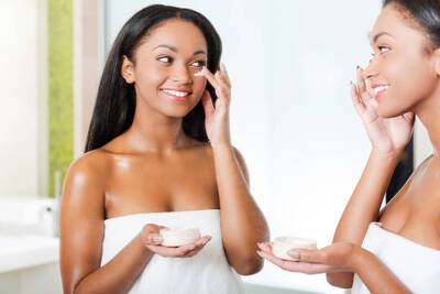 Mulher aplicando locao e creme hidratante no rosto