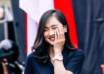 Mulher asiatica sorrindo com mao sob a face