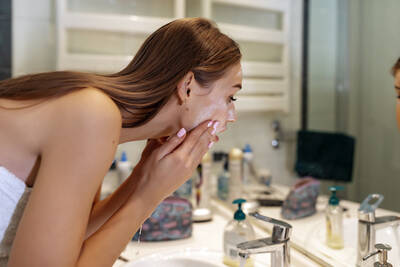 Mulher aplicando produtos de skincare para pele oleosa e com manchas