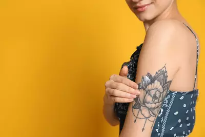 Mulher passando pomada pra tatuagem