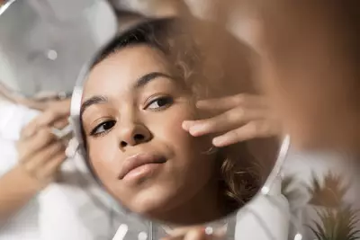 Mulher negra aplicando produtos especificos para cuidados com a sua pele
