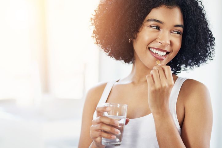 Mulher tomando uma capsula de multivitaminico