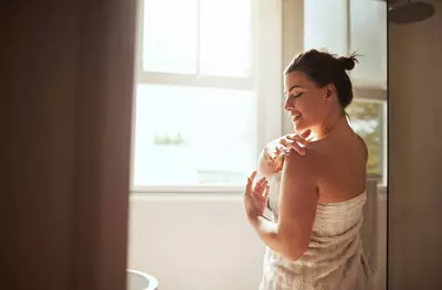 Mulher passando hidratante na pele apos o banho