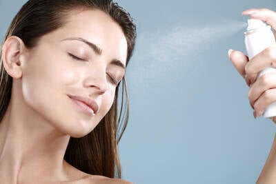 Mulher aplicando agua termal no rosto, representando como o produto pode ser benefico para a pele.