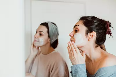 Mulheres fazendo skincare em frente ao espelho com argila branca, um ingrediente natural que purifica e suaviza a pele.