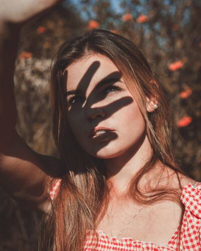 Mulher aplicando protetor solar no rosto, ressaltando a importancia do uso diario do produto para prevenir o envelhecimento precoce.