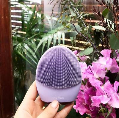 Mulher usando escova de silicone eletrica Foreo para limpeza facial