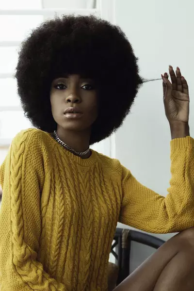 Mulher preocupada com a queda de cabelo, questionando se a perda de fios e normal ou excessiva.