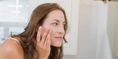 Mulher mostrando areas afetadas por melasma no rosto e aplicando creme clareador especifico