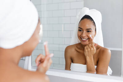 Mulher realizando skincare e se olhando no espelho