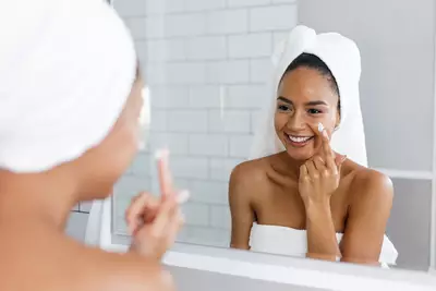 Mulher realizando skincare e se olhando no espelho