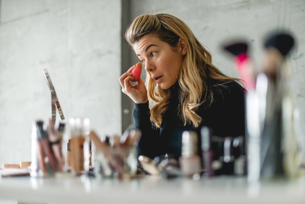 Mulher aplicando base com esponjinha para fazer a maquiagem durar mais