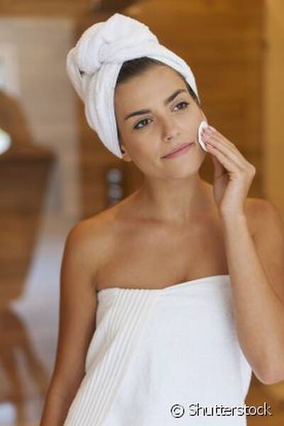 Mulher aplicando tonico facial no rosto, destacando os beneficios do produto para a pele.