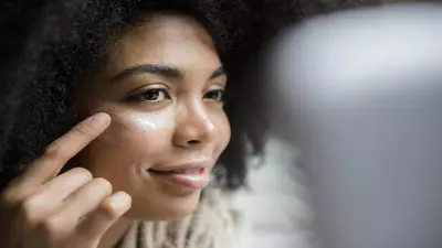 Mulher jovem aplicando Vitamina C no rosto, um ativo clareador que ajuda a reduzir manchas na pele.