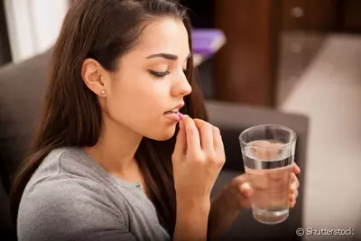 Mulher segurando uma pilula anticoncepcional, representando como esse medicamento pode afetar a pele.