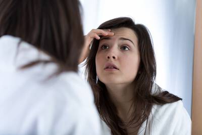 Mulher examinando a pele com acne no rosto, com diferentes tipos de espinhas e cravos