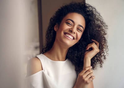 Mulher sorrindo com cabelos cacheados saudaveis