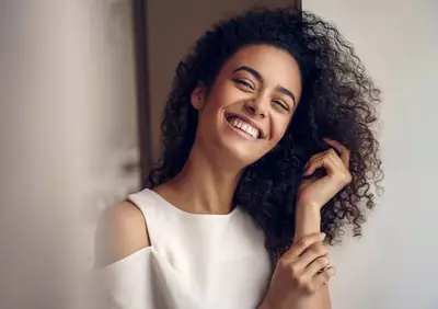 Mulher sorrindo com cabelos cacheados saudaveis