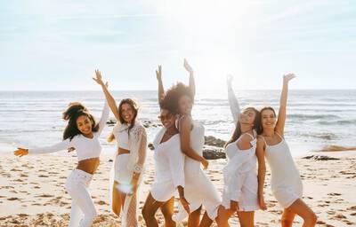 Grupo de mulheres usando branco em praia para celebrar 2026
