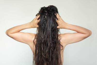 Jovem mulher tocando o couro cabeludo para cuidar do cabelo