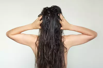Jovem mulher tocando o couro cabeludo para cuidar do cabelo