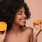 Mulher com laranja para representar o uso da vitamina c