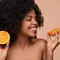 Mulher com laranja para representar o uso da vitamina c