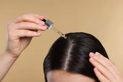 Pessoa usando oleo de cabelo no couro cabeludo