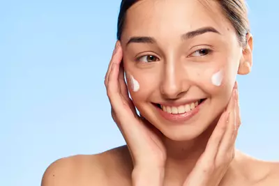 Mulher jovem passando Locao hidratante facial CeraVe AM FPS50
