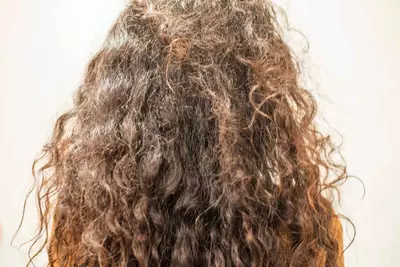 Mulher de costas com frizz no cabelo cacheado