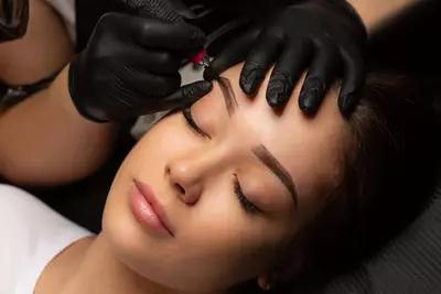 Esteticista aplicando tecnica de sobrancelha fio a fio com equipamento de micropigmentacao