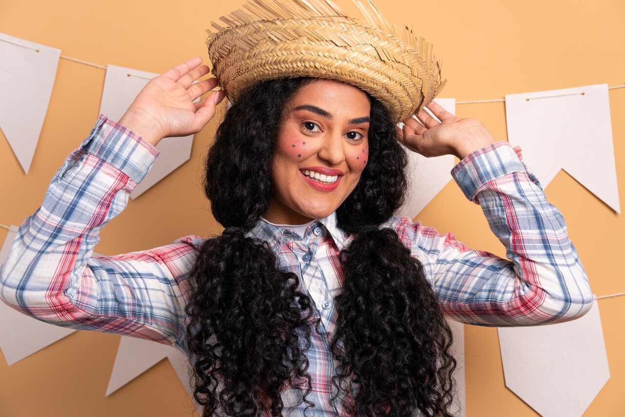 Penteado com maria-chiquinha e trancas laterais, decorado com fitas coloridas e lacos, tipico de festa junina, em uma mulher sorrindo.