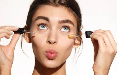 Mulher com dois conta gotas contendo retinol e retinal
