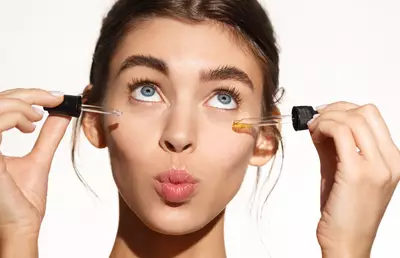 Mulher com dois conta gotas contendo retinol e retinal