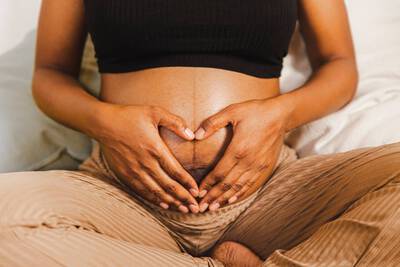 Mulher com maos sob sua barriga gravida