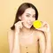 Mulher segurando uma laranja para representar o uso de vitamina c no rosto