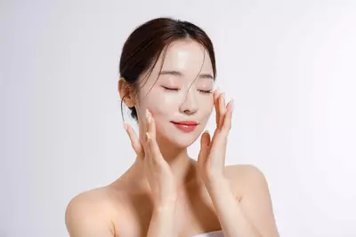 Foto de mulher aplicando serum de vitamina c no rosto.