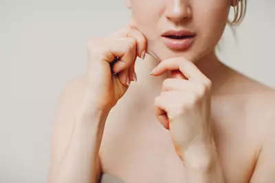 Foto de uma mulher jovem puxando a pele do queixo para mostrar a flacidez no rosto, enquanto se perunta qual o melhor colageno para flacidez do rosto