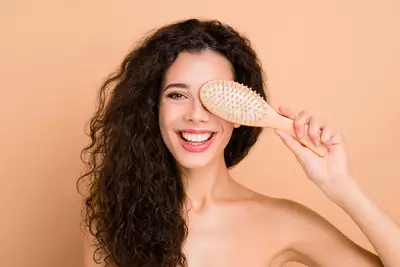 Mulher com cabelo ondulado segurando escova para pentear cabelo com pontas duplas