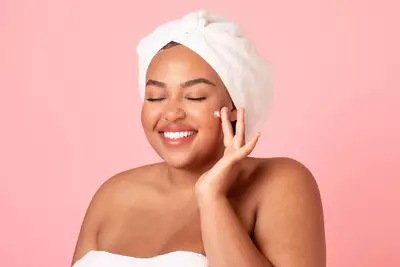 Mulher negra utilizando hidratante facial no rosto