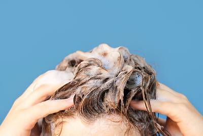 Mulher aplicando shampoo e condicionador no cabelo