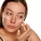 Mulher aplicando creme para manchas no rosto