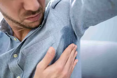 Homem com hiperidrose (suor excessivo), destacando as causas e tratamentos para a condicao.