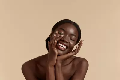 Mulher sorridente com a pele oleosa com as maos em seu rosto