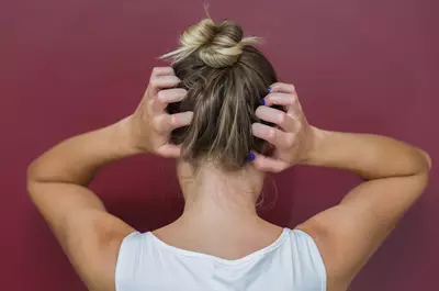 Mulher com sintomas de caspa cocando o cabelo