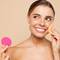 Mulher com maquiagem natural segurando esponja rosa em fundo bege