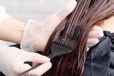 Mulher passando tonalizante para cabelo