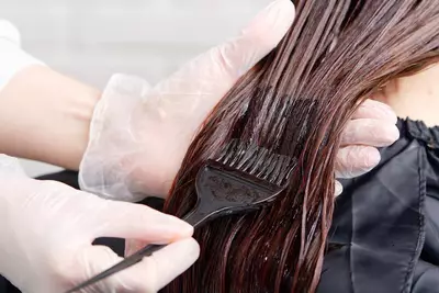 Mulher passando tonalizante para cabelo
