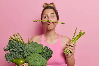 Mulher em fundo rosa segurando vegetais para alimentacao saudavel